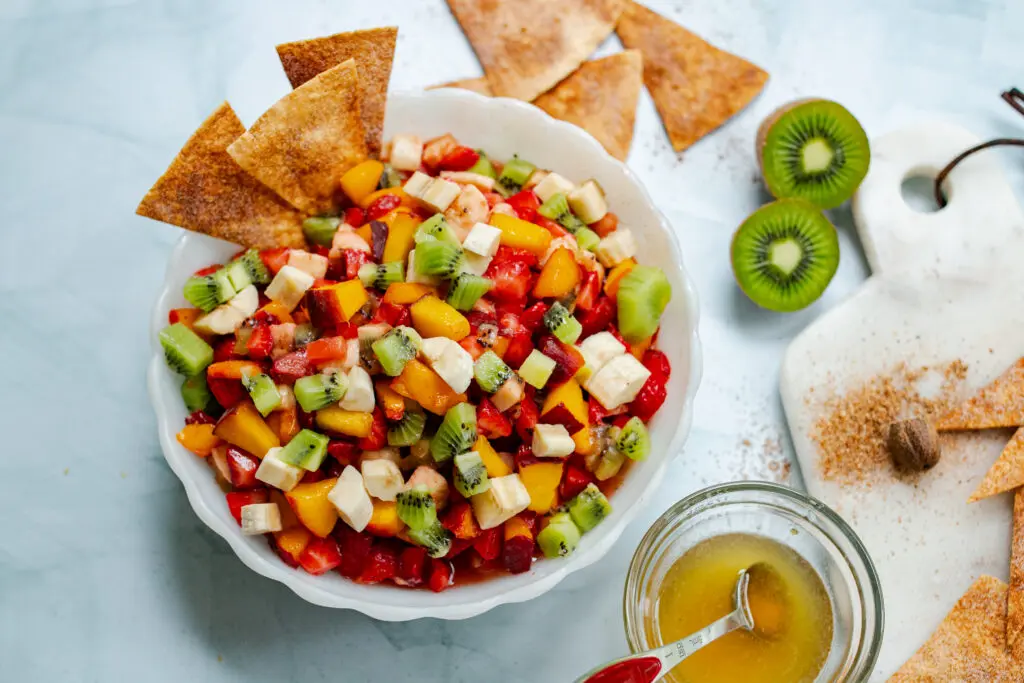 Try this recipe for a delicious summer fruit salsa. Fruit salsa in a white bowl on table.