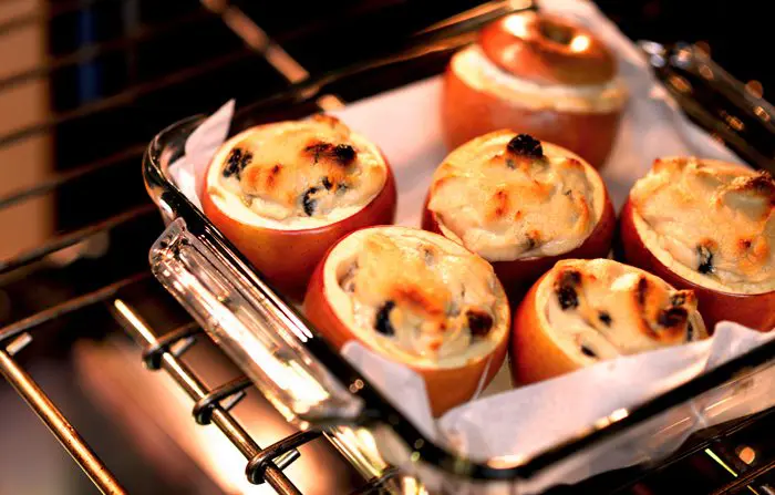 Ramekins filled with a baked, golden-brown dessert are cooling on the rack of an open oven.