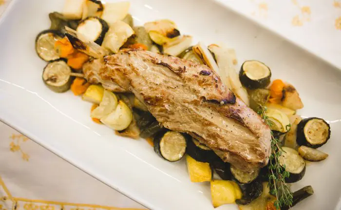 Pork tenderloin and squash vegetables served on a white platter.