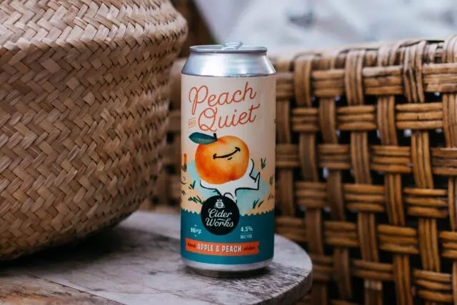 Peach & Quiet Hard Cider close up with wicker baskets.