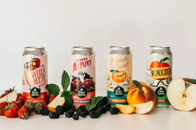 Hard Cider Variety Pack lined up with fruit in front of can.