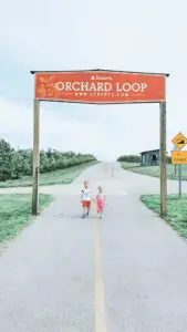 A picture of two children walking underneath Eckert's Orchard Loop sign