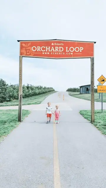 A picture of two children walking underneath Eckert's Orchard Loop sign