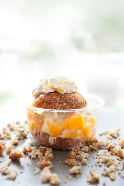 Cider donut topped with vanilla custard, sliced peaches and whipped cream