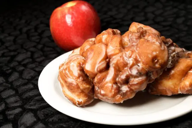 Apple Fritters on white platter with whole apple display.