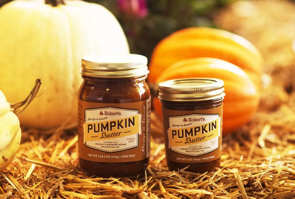 Two jars of Eckert's Pumpkin Butter sitting on straw with pumpkins in background.