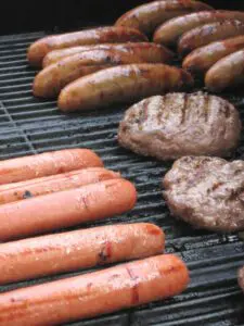 A picture of hotdogs, hamburgers, and bratwurst on a grill