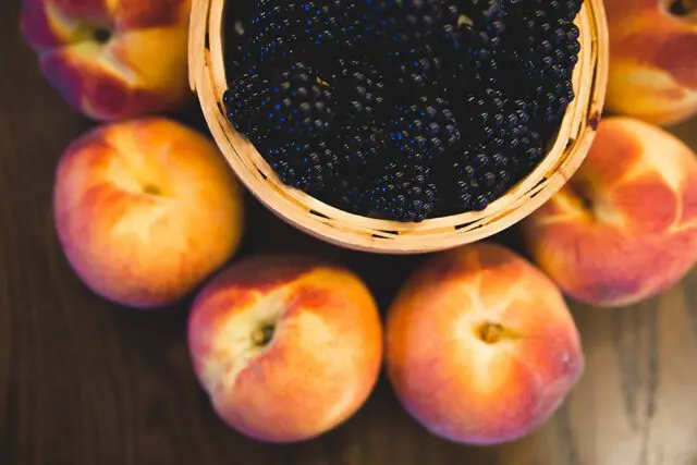 Whole peaches and blackberries in a basket
