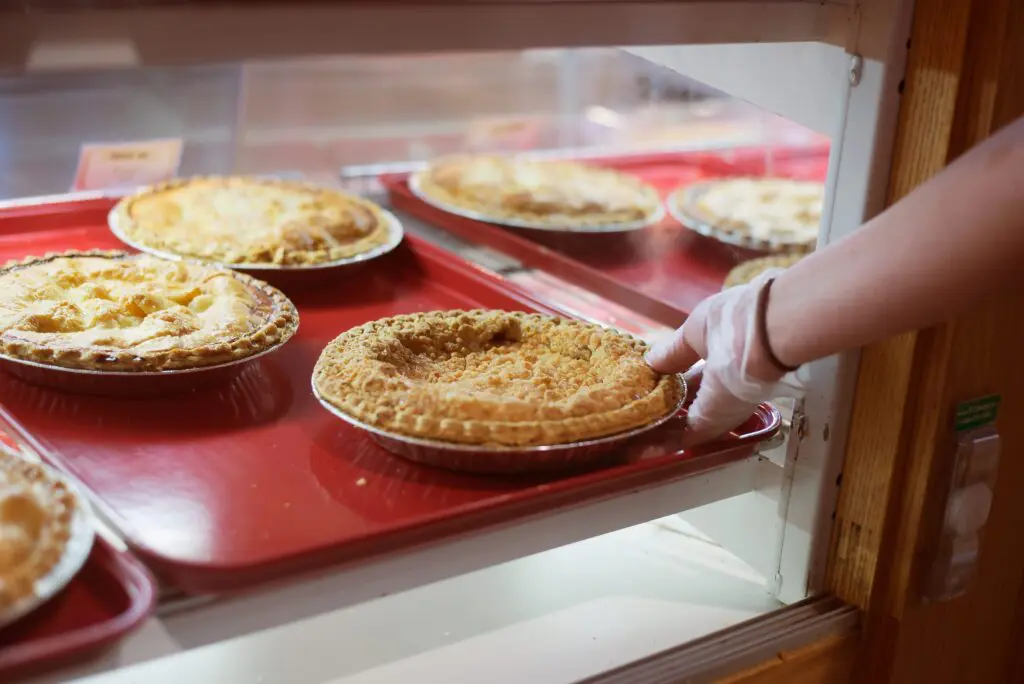 A picture of an employee placing a pie in the glass display case
