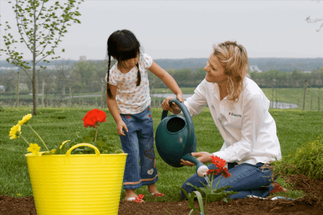 Woman Helping Girl Water Plants