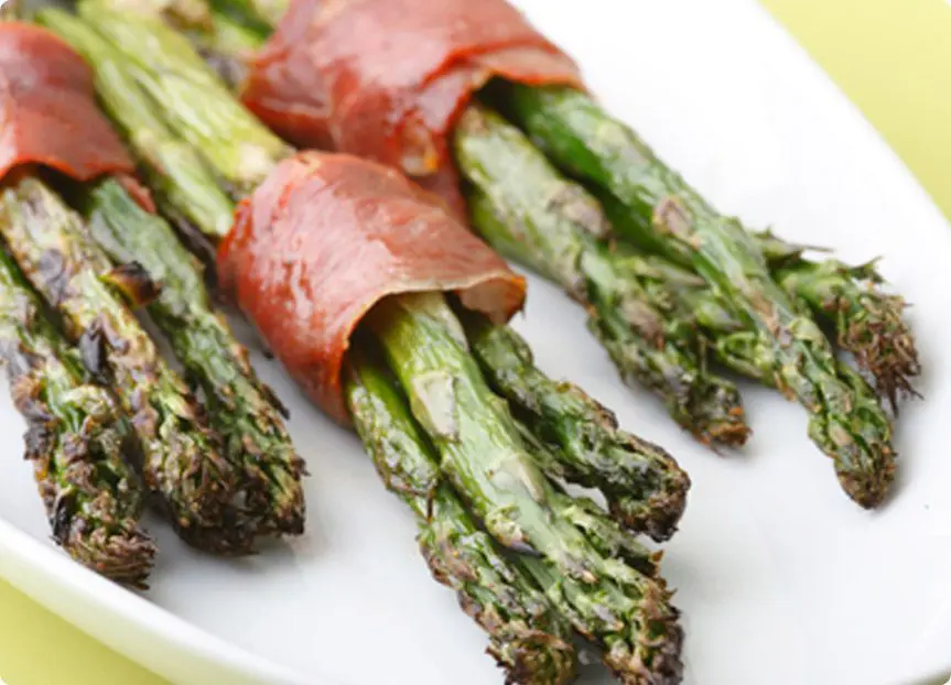 A picture of Roasted Asparagus with Prosciutto served on a white pllatter.
