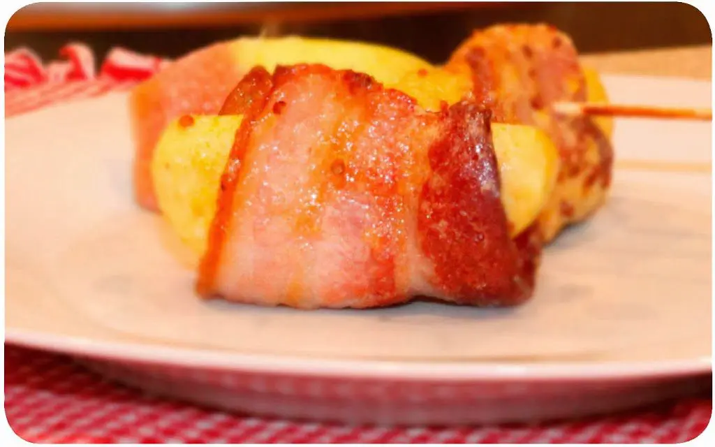 Bacon Wrapped Fuji Apples on a white plate with red checked cloth.