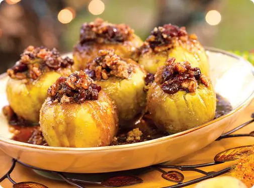 A picture of baked Eckert's apples covered in sauce served in a white bowl.