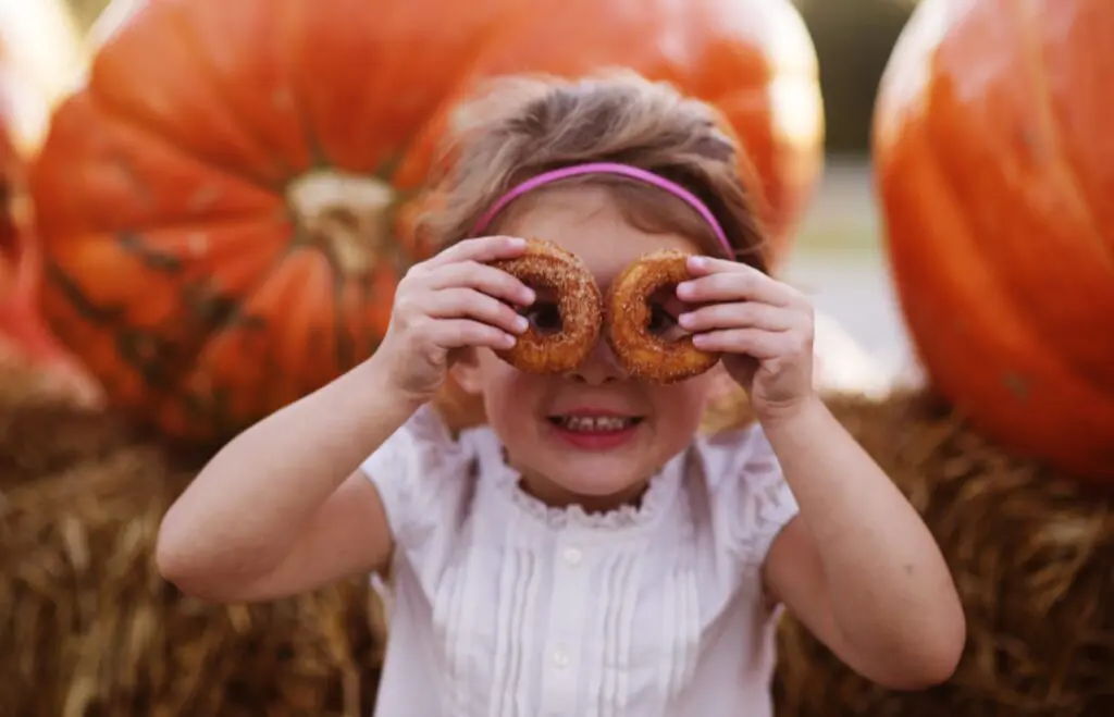Cider Donuts as Eyes with big pumkins in background.