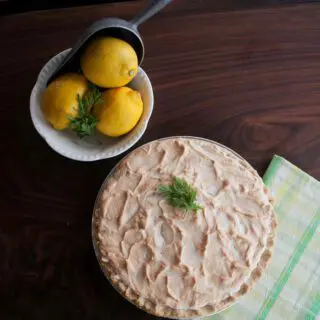 Lemon Meringue Pie with lemons and scoops in white bowl.