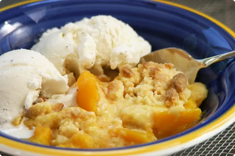 Peach Cobbler with custard in a blue bowl.