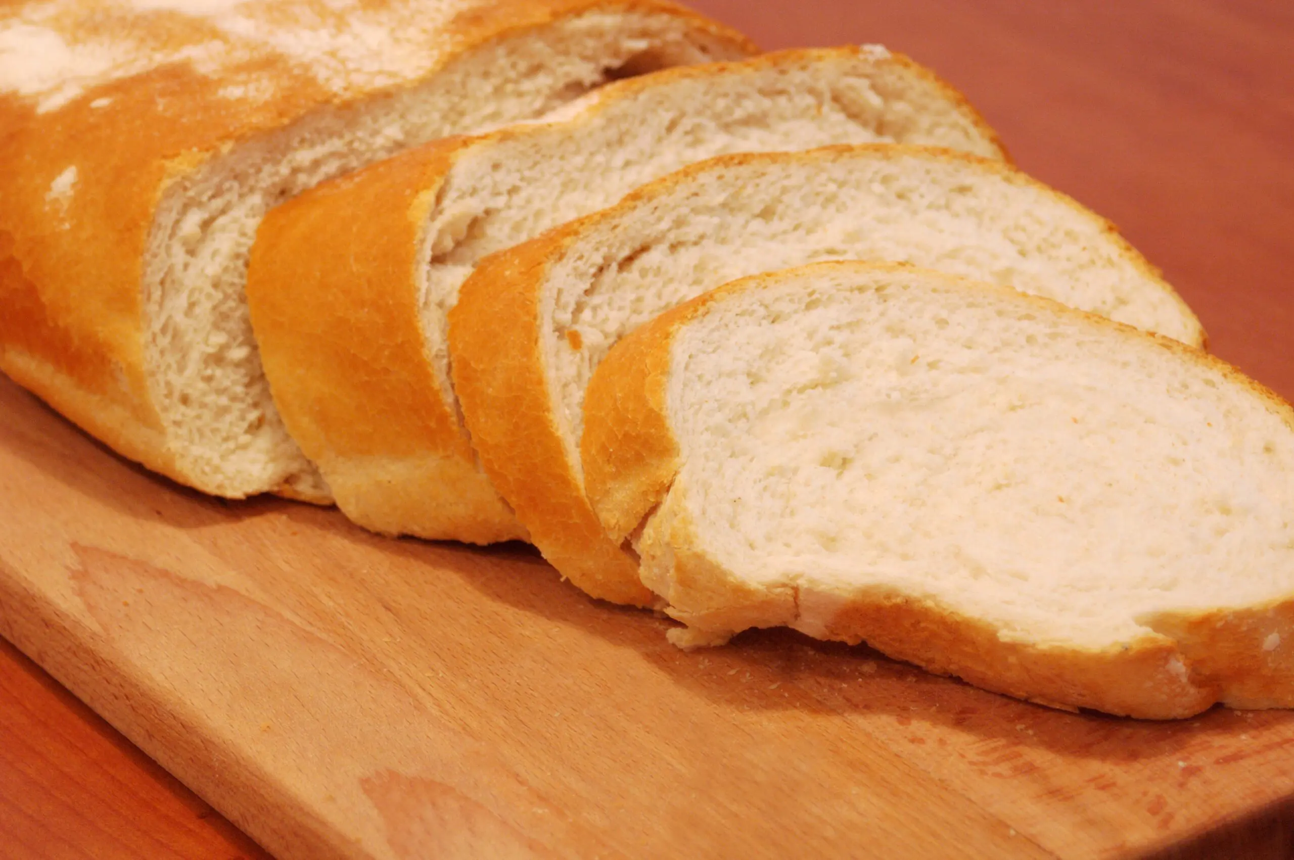 Sliced white bread on a wooden cutting board.