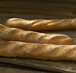 Two freshly baked baguettes rest on a rustic wooden surface.