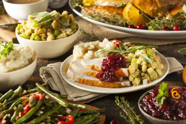 A traditional Thanksgiving dinner spread with turkey, cranberry sauce, mashed potatoes, stuffing, and green beans.
