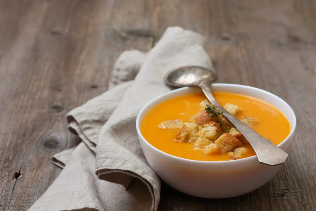Pumpkin Ginger Soup on table with spoon and napkin.