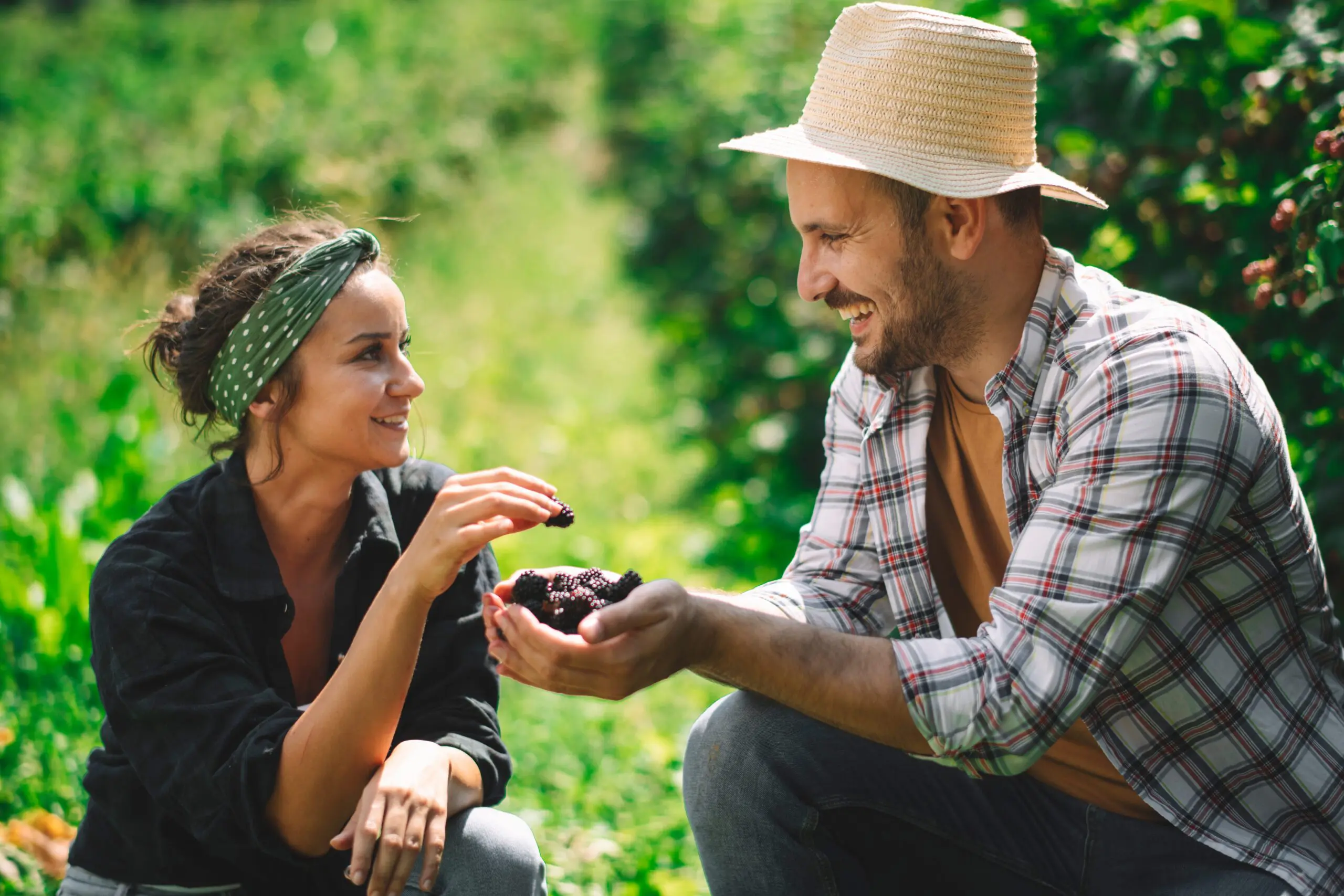 Blackberry Date Night. Man and Women kneeling, laughing and eating berries.