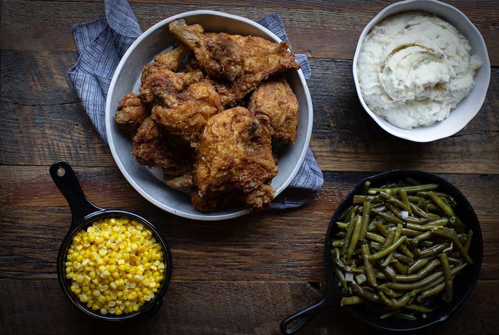 A picture of a chicken dinner with corn, green beans, and mashed potatoes