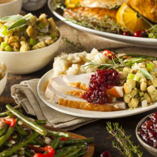 A table is adorned with a variety of Thanksgiving dishes, including turkey, green beans, cranberry sauce, and other seasonal sides.