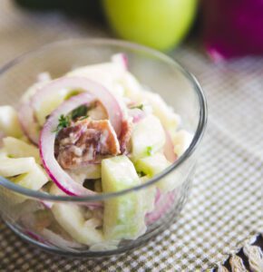 A bowl of fresh ceviche with fish, lime, onions, and herbs on a textured surface.